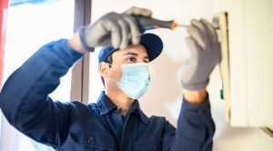 An HVAC technician using a screwdriver