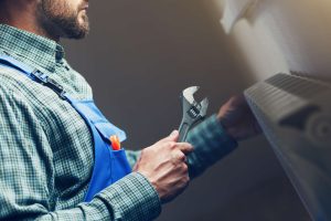 A man holding a wrench and wearing an apron